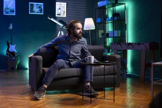 Livid supporter watching in disbelief own team getting defeated during live match broadcast, expressing anger. Mad man jumping from couch in frustration seeing favorite club commit blunder photo