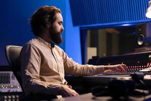 Sound expert working on recording and composing new tracks, processing audio files and using mixing console in control room. Producer twisting knobs and switchers in music production studio. photo