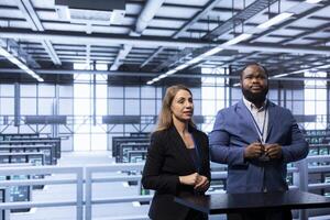 Admins in data center tracking network traffic and activity using augmented reality technology and installing software updates. Coworkers performing database backups using AR tech visualization photo