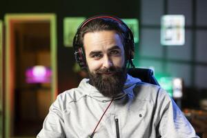 Portrait of smiling man recording himself competing in videogame tournaments online while streaming on internet channel. Cheerful pro gamer participating in esports tourney during livestream photo