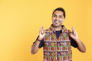 Portrait of joyous man crossing fingers, waiting to receive good news, isolated over studio background. Radiant person with positive mood hoping for good luck, aspiring for miracle photo