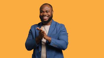 Approving smiling african american man happily clapping hands, satisfied with accomplishments. BIPOC person cheering, doing praising gesture, isolated over studio background, camera A photo