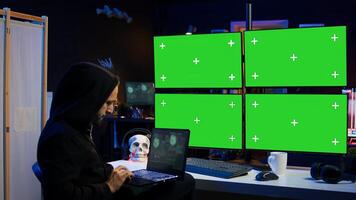 Man writing code on laptop in front of isolated screen PC monitors, trying to get past security systems. Hacker using chroma key computer and notebook to make scripts that can hack devices, camera B photo
