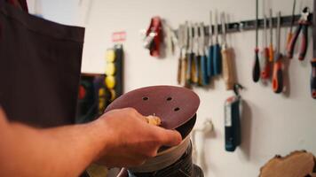 Craftsperson putting sandpaper discs on sander device to be used on smoothing wood surfaces. Woodworking expert preparing necessary gear for furniture assembling commission, close up, camera B photo