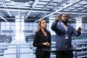 Coworkers using AR in data center, ensuring cybersecurity and efficient network management. Engineers in server hub optimizing data center equipment with augmented reality technology photo