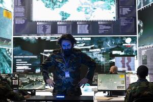 Army conscript examines satellite data on a hologram projection, monitoring registered information from radar surveillance system. Looking at new defense mission details in military base. photo