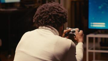 BIPOC gamer playing classic arcade space shooter videogame on ultrawide smart TV, shooting asteroids. Close up shot of man using gaming console to solve missions in singleplayer game photo