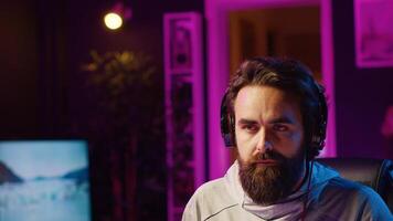 Close up shot of man putting headphones on while playing videogames at home to better immerse himself. Player participating in online multiplayer esports tournament, fighting to defeat enemies photo