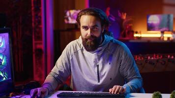 Content creator playing videogames live while chatting with online audience from neon lit apartment. Pro gamer streaming multiplayer game while discussing his strategies with viewers photo