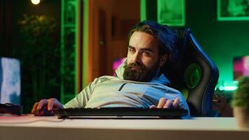 Gamer having seizure while at computer desk, exhausted after pathologically playing videogames all day. Lethargic man falling asleep, crashing with chair from fatigue, suffering from gaming addiction photo