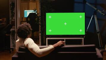 Person using chroma key projector to binge series on subscription based streaming services. Cord cutter relaxing on couch, enjoying on demand shows on mockup smart TV photo