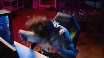 Angry man playing videogames at home, smashing head on keyboard after being defeated by enemies. Competitive pro gamer raging after failing to win online multiplayer esports match, feeling annoyed photo