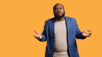 Uncaring man shrugs shoulders, showing indifference and apathy while talking with friend. Careless person doing nonchalant indifferent hand gesturing during conversation, studio background, camera B photo