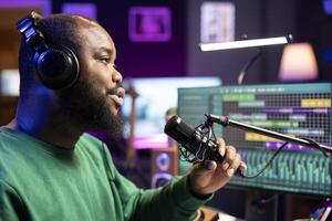 Artist producer singing a new song to record on microphone, preparing to edit music in post production. Musician expert applying mixing and mastering techniques on his audio recorded files. photo