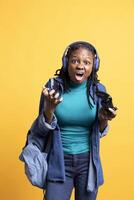 Angry gamer raging and screaming after receiving game over screen, holding controller. Irked african american woman yelling after losing videogame, playing with gamepad, studio background photo