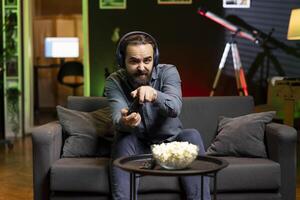Man holds motion sensitive controller, playing racing videogames and wearing headphones. Gamer using joystick gyroscope function to participate in PvP online game, talking with friends through headset photo