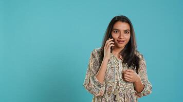Happy woman chatting with best friend over telephone call, enjoying relaxation time. Upbeat person communicating with mate using phone, isolated over studio background, camera B photo