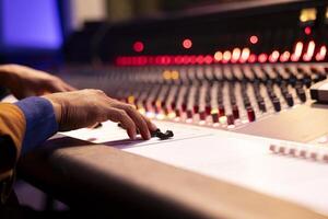 Audio expert recording and editing music with mixing console panel board, twisting knobs and changing sound settings in studio. Music producer working in control room. Close up. photo
