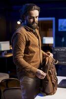 Programmer closing backpack, leaving office after filtering malicious traffic from cybercriminals attempting to steal company data. Man finishing job shift after being done with preventing malware photo