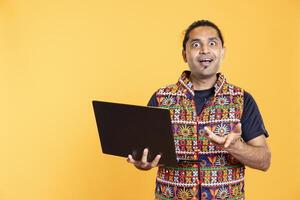 Portrait of employee with astonished look on face after receiving promotion at work, isolated over studio background. Overjoyed worker excited after reading good news on email on laptop photo