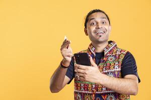 Portrait of cheerful man adding payment method on phone website, delighted to take advantage of promotions. Overjoyed person thrilled to do internet shopping on smartphone, studio backdrop photo