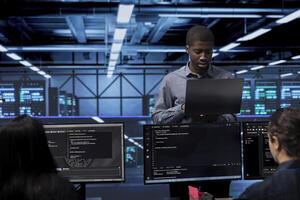 Admin doing routine maintenance in data center to extend equipment life span and avoid downtime. Worker monitoring servers for issues such as overheating or power fluctuations photo