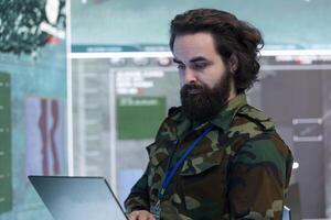 Technical engineer gathers intelligence from world map projection, connected to satellite reconnaissance system to support field troops with real time data. Dispatch army command post. photo