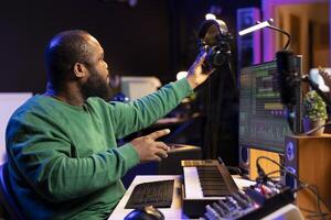 Audio technician works with recording tools in his home studio, using mixing console and pre amp knobs to add sound effects on tracks. Composer editing new tunes in post production. photo