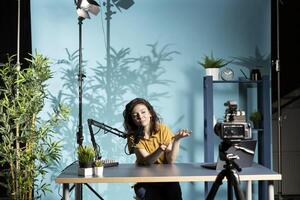 Influencer hosting internet show, speaking into professional mic, recording live stream with camera. Content creator smiles while engaging with audience, discussing in high tech workspace photo