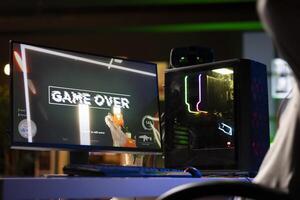 Upset gamer feeling depressed after losing online competitive multiplayer match, playing on gaming setup. Player feeling angry and shouting after being defeated in videogames photo