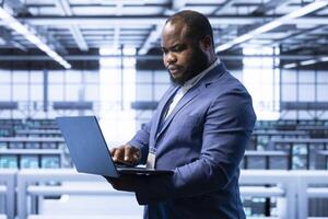 Software developer in data center monitoring system performance, identifying bottlenecks and implementing optimizations. Supervisor in high tech server hub workspace troubleshooting bugs photo