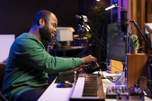 Talented musician creating new soundtracks on mixing console, operating on audio equipment in home studio. Sound technician twisting knobs to edit volume levels on his melody. photo