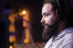 Pro gamer at home talking with teammates, competing together in intense online multiplayer videogame, close up. Man having gaming session with friends, using powerful computer, speaking in mic photo