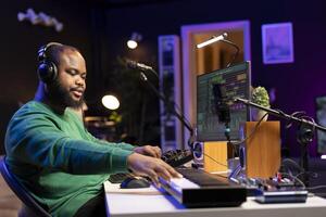 Audio designer enhancing sound quality on his audio files with mixing console and amplifier, editing in post production. Skilled music producer operating faders and pre amp knobs. photo