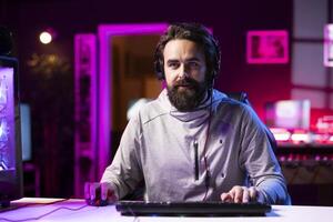 Person using headphones microphone to talk with teammates while playing FPS videogame with gun shooting laser bullets. Gamer chatting with internet friends while enjoying SF game, having fun photo