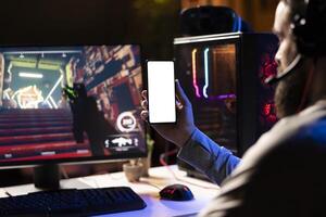 Man watching favorite content creator on isolated screen smartphone showing tips for game he is currently playing, close up. Player looking online for inspiration on mockup phone, stuck on mission photo