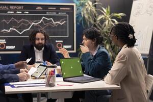 Business associates attending conference next to greenscreen laptop, deciding the fate of the global organization and working on developing resources. Operations team addressing daily issues. photo