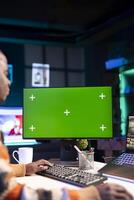 Videographer creating visual effects on montage next to green screen, working on color correction to edit footage and frames. Freelancer content creator editing clips on computer software. photo