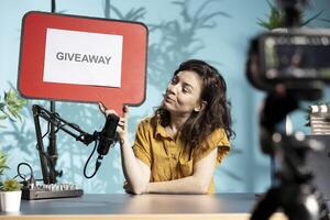 Influencer filming sponsored content, holding copy space sign advertising giveaway, talking to audience. Internet star using cardboard bubble speech cutout to do content promotion to viewers photo
