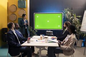 Sales team working with isolated copyspace display on tv in a briefing meeting, sharing ideas and impressions to improve organizational workflow. Enterprise affiliates gathered in a conference. photo