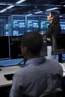 Manager in server hub using computer to find firewall misconfigurations affecting rackmounts performance. Supervisor checking systems bottlenecks leading to sluggish data transfer rates photo