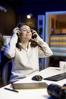 Photographer using photo editing software on PC display in multimedia creative studio while listening to music. Freelancer using photographs retouching program, hearing songs through headphones