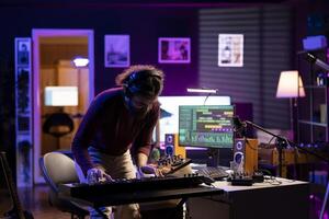Confident singer playing new song on electronic piano keyboard in home studio, recording new music and having fun with stereo gear. Joyful artist performer plays tunes on midi controller synthesizer. photo