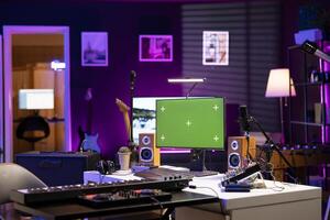 Empty home studio with computer running greenscreen display, audio equipment and mixing instruments used for recording tunes. Music production and acoustics gear in modern space. photo