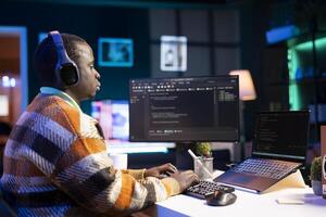 Black software engineer writes complex binary code scripts on computer, cybersecurity. Teleworking IT specialist in home office using programming language to safeguard consumer data. photo