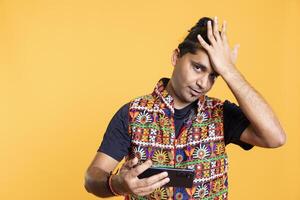 Gamer annoyed after losing online multiplayer videogame on cellphone, doing facepalm hand gesture. Player feeling frustrated after failing to win, isolated over studio background photo