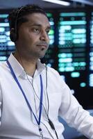 Data center high tech facility technician responsible for providing logistics support to customers. Man in server room overseeing infrastructure systems and communicating with engineers photo