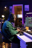 Skilled music producer composing new soundtracks on console and daw software, working with stereo gear in home studio. Young artist engineer uses pre amp knobs, signal processing. photo