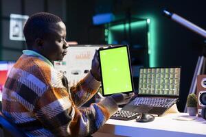 Accountant working from home with legal trade analysis and green screen, calculating revenue and costs for monthly balance. African american advisor examining global investment elements. photo