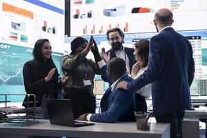 Diverse enterprise team enjoying huge global expansion progress, feeling excited about the future and celebrating a successful partnership outcome. High five between employees. photo